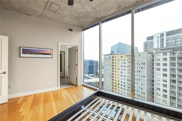 44 Peachtree Pl NE Unit 1824, Atlanta, GA 30309 - unfurnished bedroom featuring wood finished floors, floor to ceiling windows, a city view, and baseboards