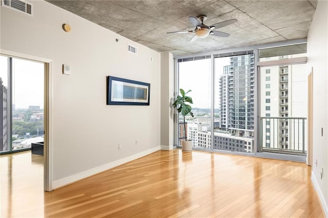 44 Peachtree Pl NE Unit 1824, Atlanta, GA 30309 - spare room with wood finished floors, plenty of natural light, ceiling fan, expansive windows, and baseboards