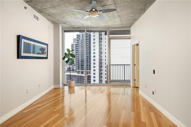 44 Peachtree Pl NE Unit 1824, Atlanta, GA 30309 - spare room with hardwood / wood-style floors, floor to ceiling windows, a ceiling fan, and baseboards