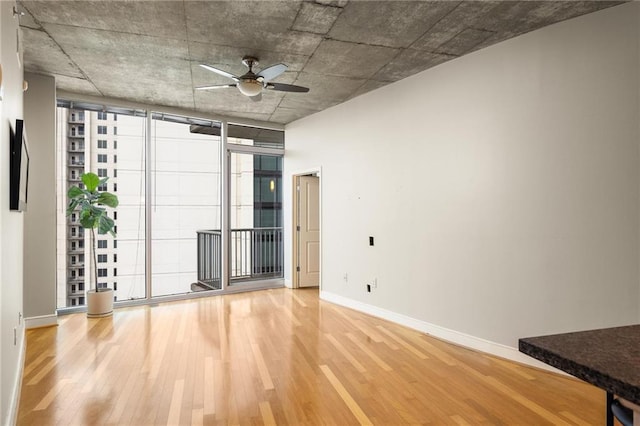 44 Peachtree Pl NE Unit 1824, Atlanta, GA 30309 - empty room with wood finished floors, ceiling fan, baseboards, and a wall of windows
