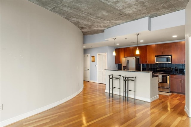 44 Peachtree Pl NE Unit 1824, Atlanta, GA 30309 - kitchen with stainless steel appliances, dark countertops, light wood finished floors, a kitchen breakfast bar, and brown cabinets
