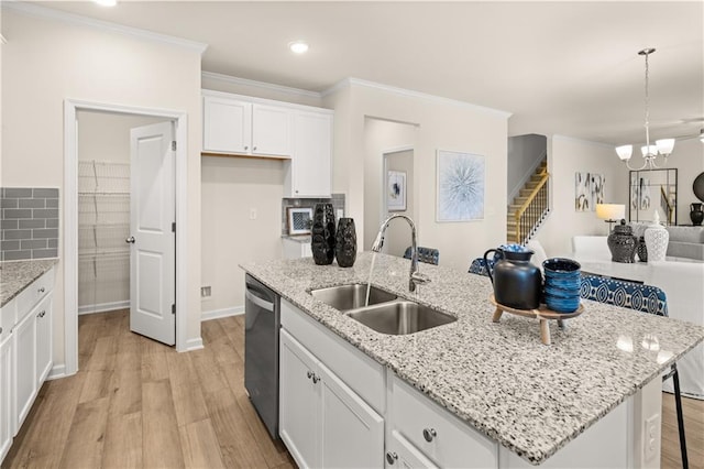 kitchen featuring dishwasher, an island with sink, white cabinetry, pendant lighting, and a sink