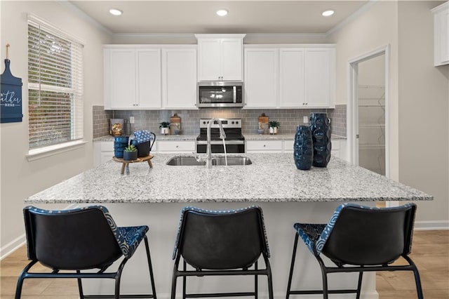 kitchen featuring a kitchen island with sink, white cabinetry, and stainless steel appliances