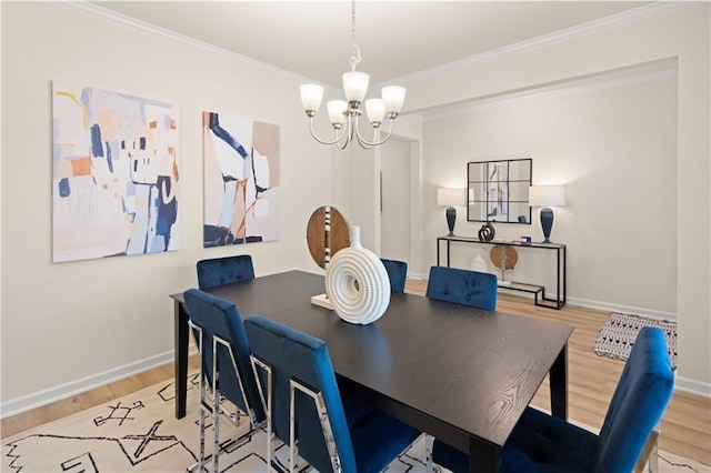 dining room featuring light wood-type flooring, crown molding, baseboards, and an inviting chandelier