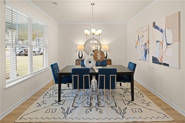 dining space with light wood-style floors, a notable chandelier, visible vents, and crown molding