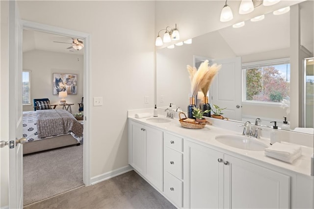 ensuite bathroom featuring ensuite bathroom, vaulted ceiling, a sink, and a wealth of natural light