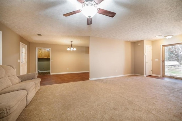 unfurnished living room with carpet, baseboards, a textured ceiling, and ceiling fan with notable chandelier