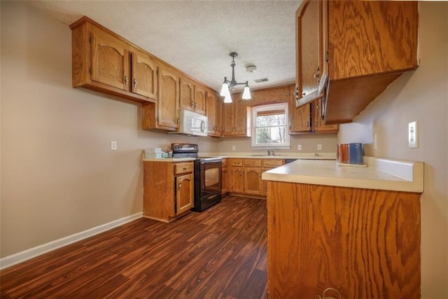 kitchen featuring electric range, brown cabinetry, a sink, and white microwave