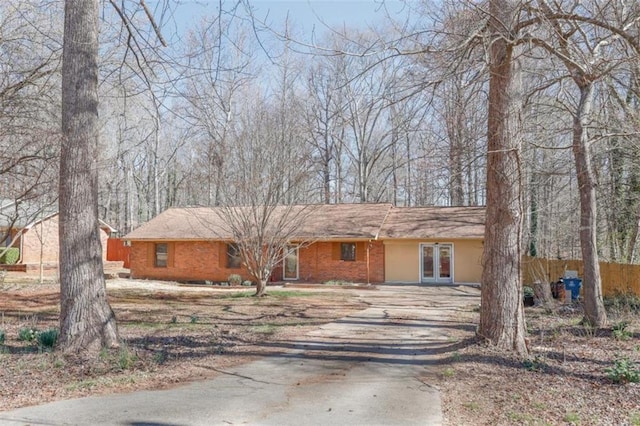 ranch-style home featuring driveway, french doors, and fence