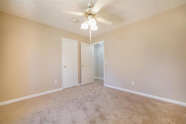 carpeted empty room with a ceiling fan and baseboards