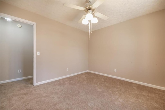 empty room featuring a textured ceiling, carpet, a ceiling fan, and baseboards