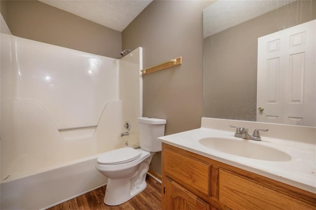 bathroom with toilet, wood finished floors, a textured ceiling, vanity, and washtub / shower combination