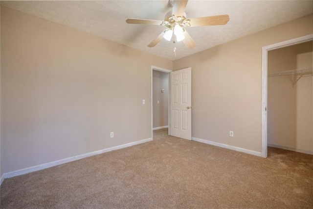 unfurnished bedroom with a closet, a ceiling fan, light carpet, a textured ceiling, and baseboards