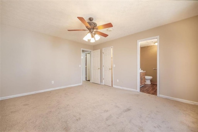 unfurnished bedroom with light carpet, connected bathroom, a textured ceiling, and baseboards