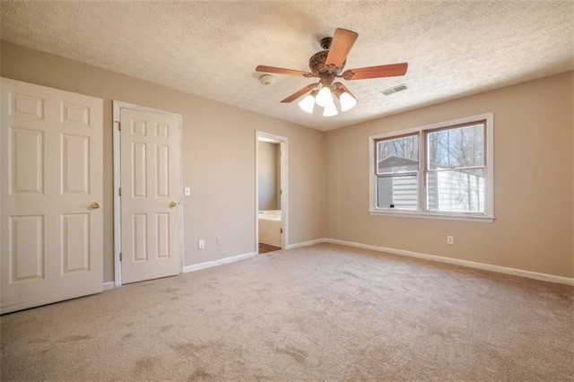 unfurnished bedroom with a textured ceiling, connected bathroom, carpet flooring, visible vents, and baseboards