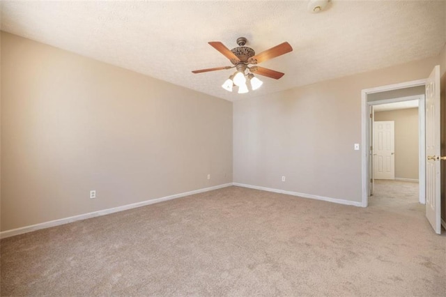 empty room with baseboards, ceiling fan, a textured ceiling, and light colored carpet