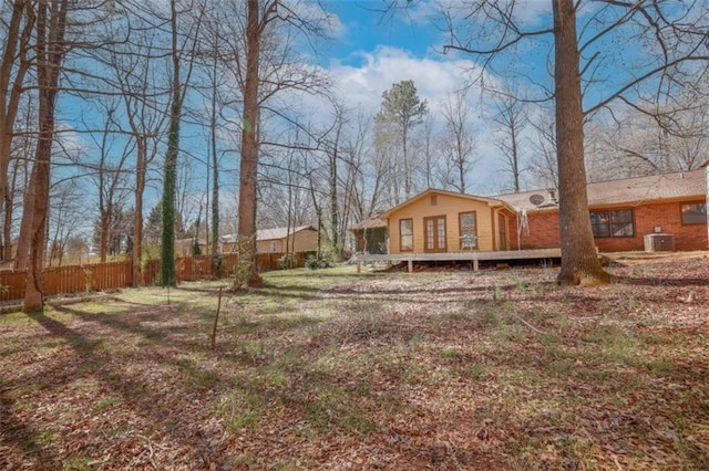 view of yard featuring fence, a deck, and central AC