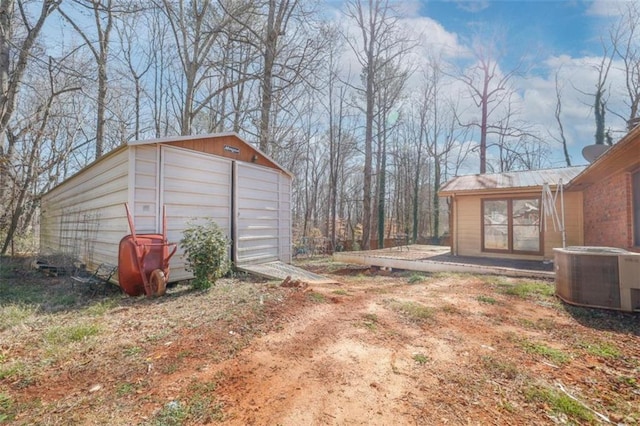 view of yard featuring a garage, cooling unit, and an outbuilding