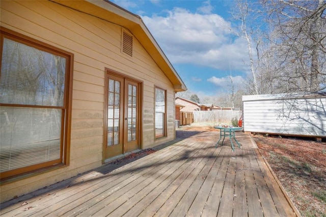 wooden deck featuring an outbuilding and fence