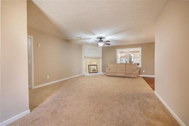 unfurnished living room with carpet, a textured ceiling, a fireplace, and baseboards