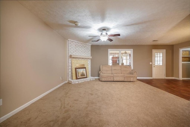 unfurnished living room featuring carpet, a fireplace, baseboards, and a textured ceiling