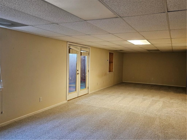 carpeted spare room featuring a drop ceiling and baseboards