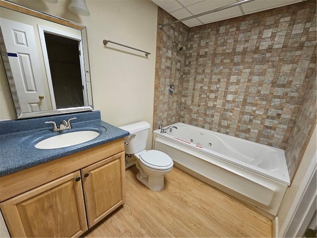 bathroom featuring a drop ceiling, toilet, wood finished floors, vanity, and  shower combination