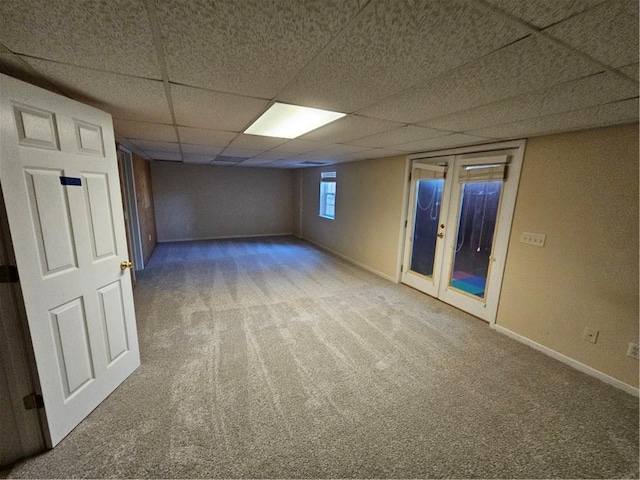 basement featuring french doors, a drop ceiling, carpet flooring, and baseboards