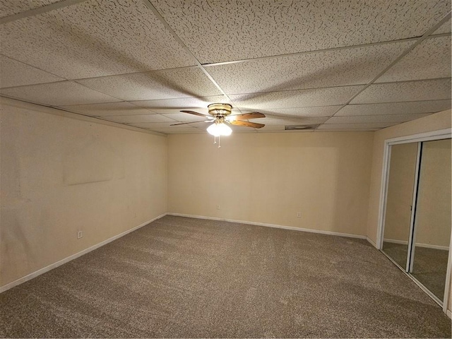 empty room with carpet floors, a paneled ceiling, baseboards, and a ceiling fan