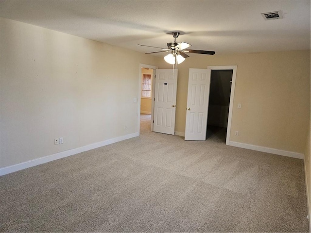 unfurnished bedroom with baseboards, visible vents, a ceiling fan, light colored carpet, and a spacious closet