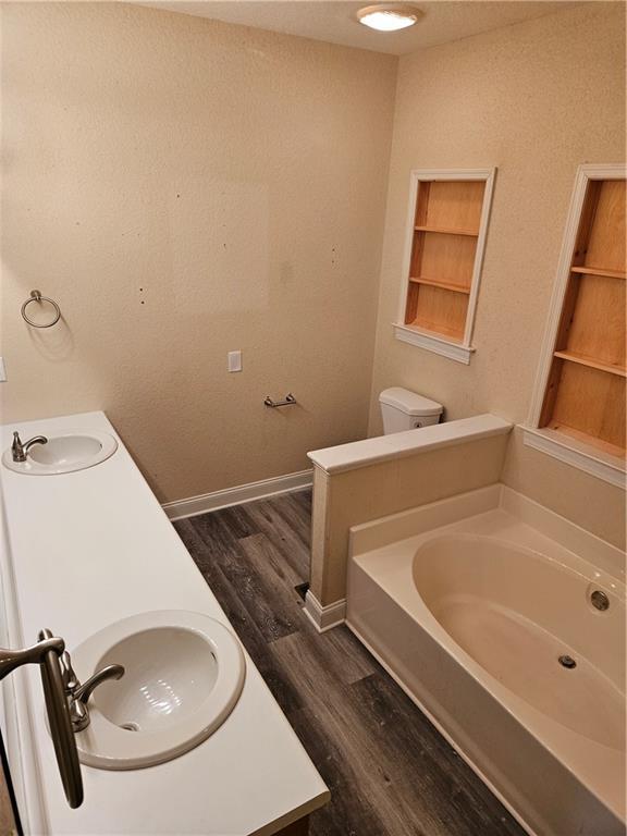 full bath with baseboards, a sink, a bath, and wood finished floors