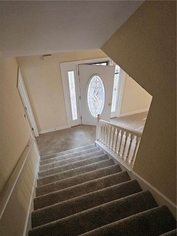 stairs with lofted ceiling, baseboards, visible vents, and carpet flooring