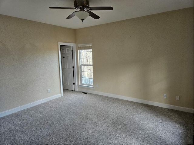 empty room with a ceiling fan, baseboards, visible vents, and carpet flooring