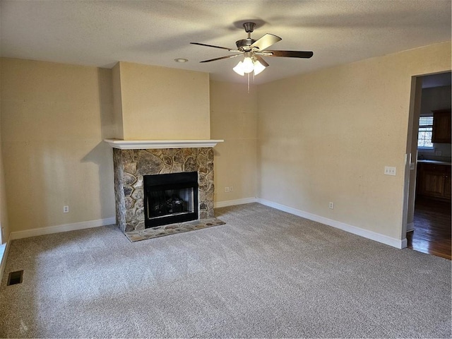 unfurnished living room with baseboards, visible vents, carpet, a textured ceiling, and a stone fireplace