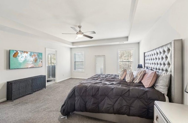 carpeted bedroom featuring a tray ceiling and ceiling fan