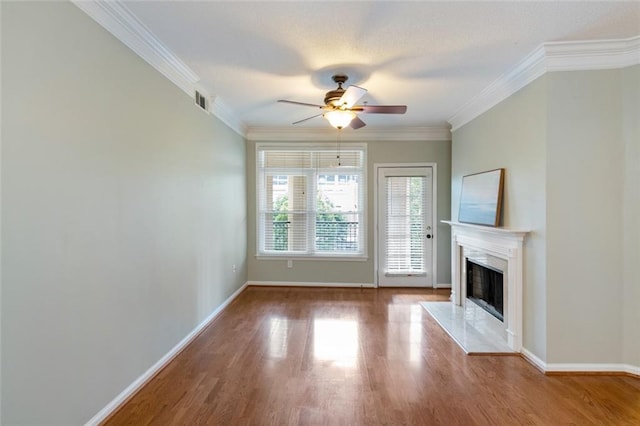 unfurnished living room featuring a high end fireplace, ornamental molding, a ceiling fan, and wood finished floors