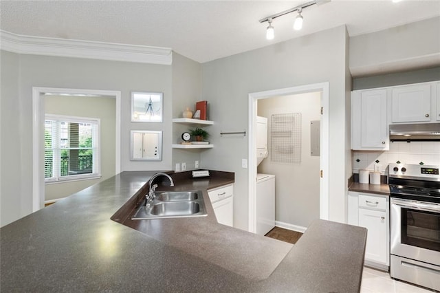 kitchen with dark countertops, stacked washer / dryer, under cabinet range hood, electric stove, and a sink