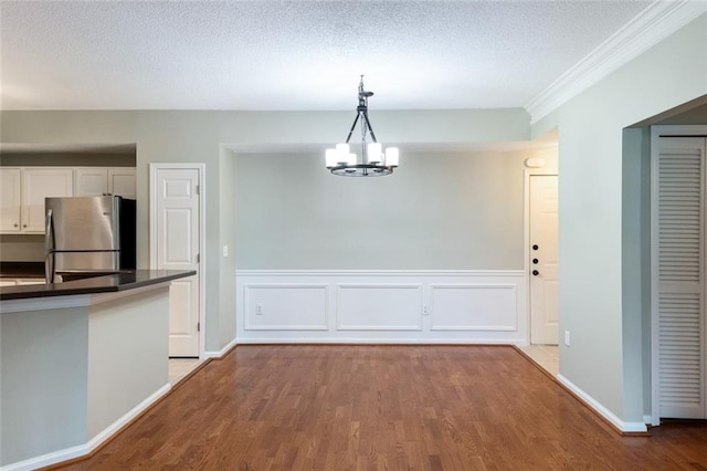 kitchen with wood finished floors, freestanding refrigerator, white cabinets, a textured ceiling, and dark countertops