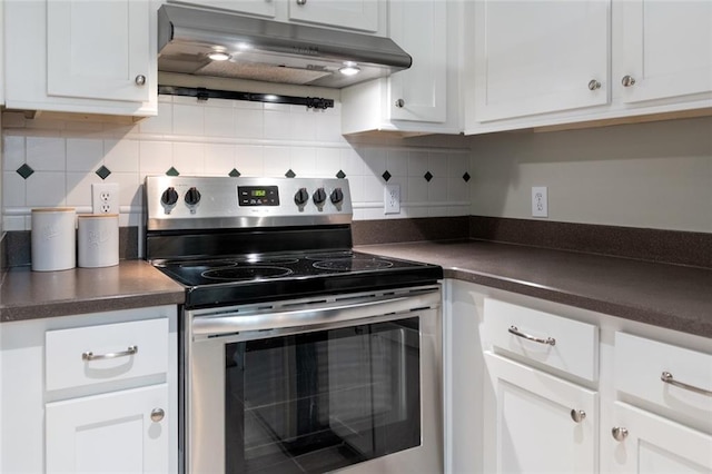 kitchen featuring under cabinet range hood, electric range, dark countertops, and white cabinets