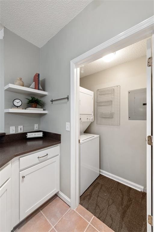 washroom with light tile patterned floors, laundry area, electric panel, stacked washer and dryer, and a textured ceiling