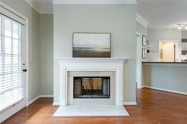 unfurnished living room with ornamental molding, wood finished floors, baseboards, and a premium fireplace