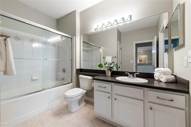 bathroom featuring tile patterned flooring, toilet, vanity, and shower / bath combination with glass door