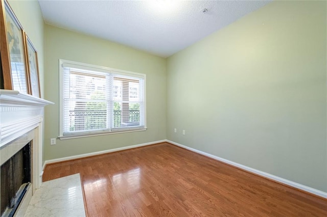 unfurnished living room featuring a fireplace, baseboards, and wood finished floors