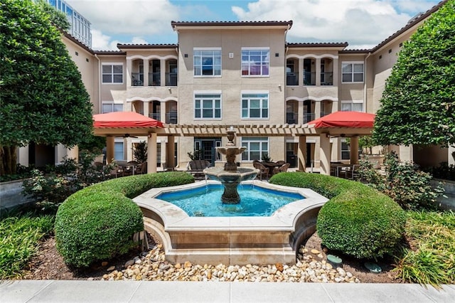 back of property featuring stucco siding, a tiled roof, and a pergola