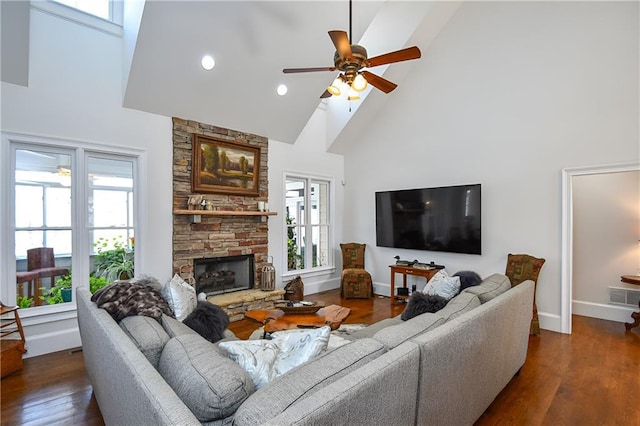 living room featuring visible vents, dark wood-style flooring, baseboards, and a stone fireplace