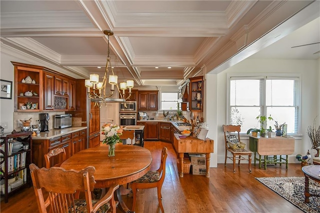 dining space with a healthy amount of sunlight, dark wood finished floors, coffered ceiling, and an inviting chandelier