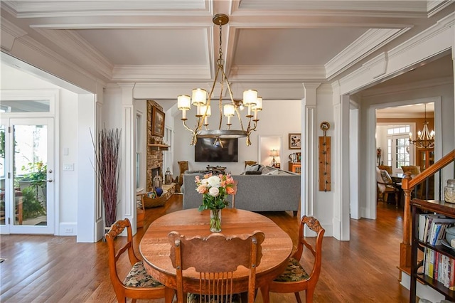 dining space featuring wood finished floors, plenty of natural light, ornamental molding, and an inviting chandelier