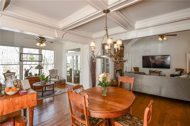 dining room featuring a stone fireplace, dark wood-style flooring, coffered ceiling, beam ceiling, and ornamental molding