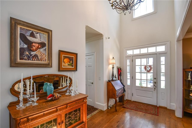 entrance foyer with wood finished floors, plenty of natural light, a high ceiling, and a chandelier