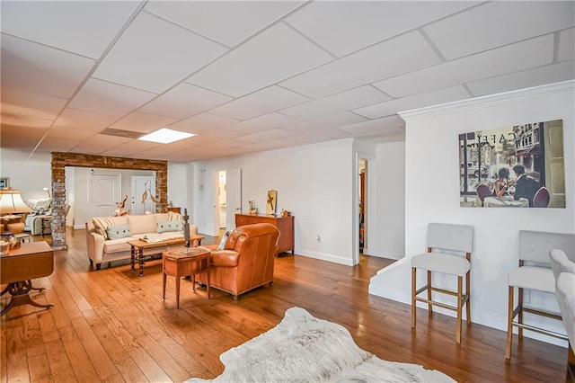 living area featuring ornamental molding, baseboards, and wood finished floors